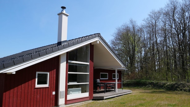 A red building with a sloped roof, a chimney, and a covered porch with outdoor furniture. - Grobenbrode Green Lawn Sanctuary (Grossenbrode)