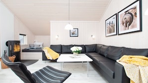 A modern living room with a black leather sofa, a white coffee table, and a fireplace. - Grobenbrode Green Lawn Sanctuary (Grossenbrode)