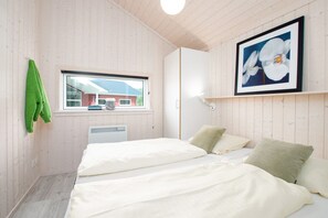 Ein Zimmer mit zwei Betten, einem Fenster, einer Heizung und einem gerahmten Bild an der Wand.