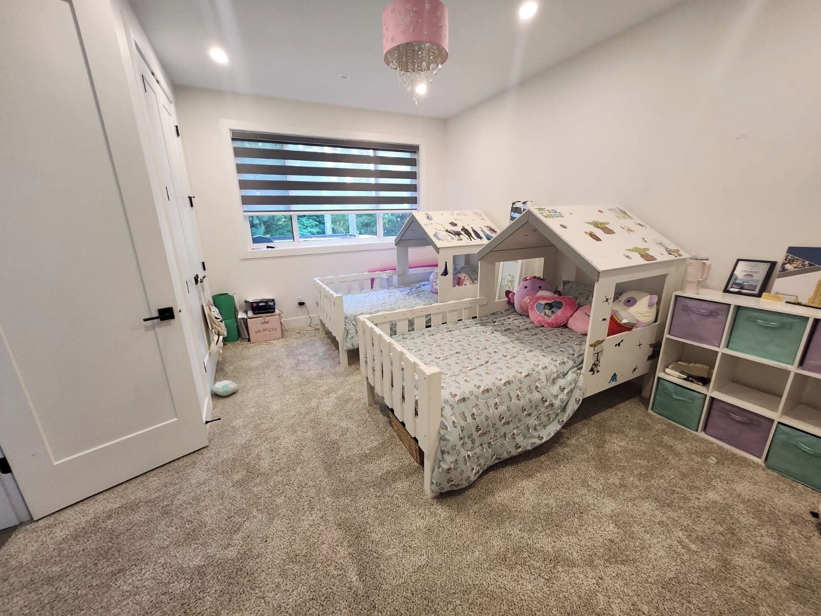 A child's bedroom with bunk beds, a window, and storage units.