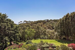 A lush garden with a variety of trees and shrubs, a well-maintained lawn, and a small wooden structure. - Caves House Hotel (Yallingup)