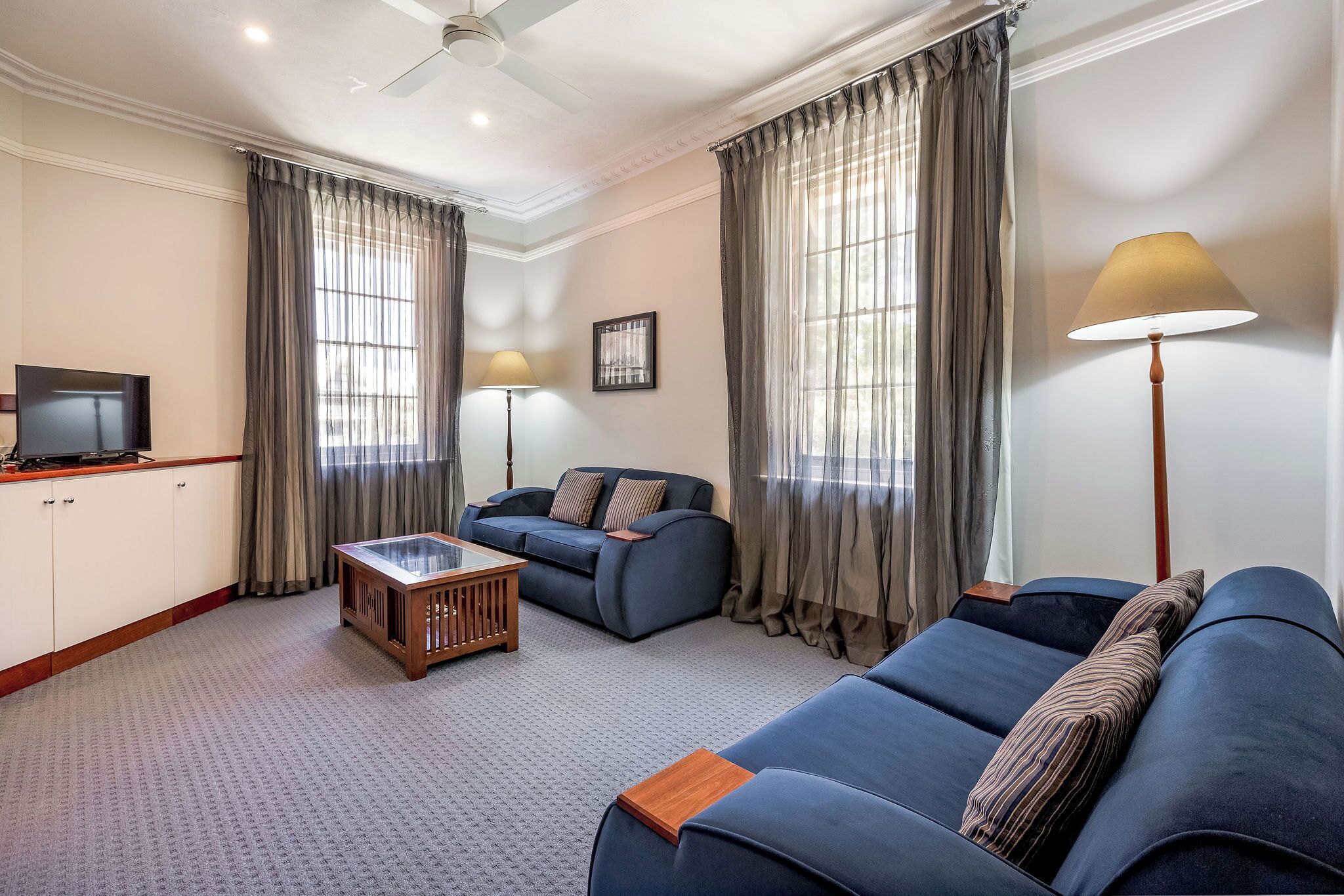 A living room with a sofa, a coffee table, a TV, and curtains.