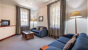 A living room with a sofa, a coffee table, a TV, and curtains.