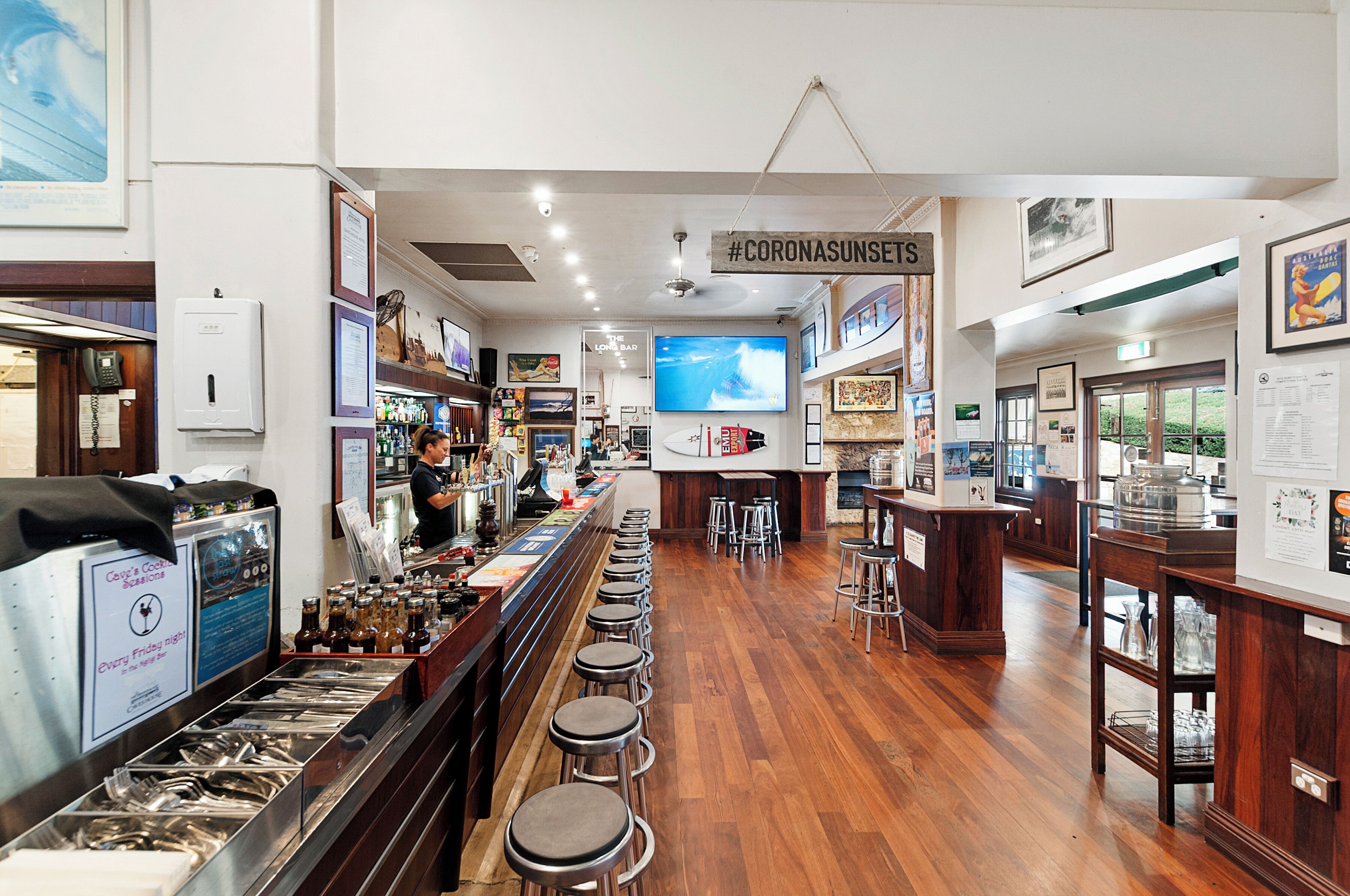 A bar area with stools, a counter, and a television screen.