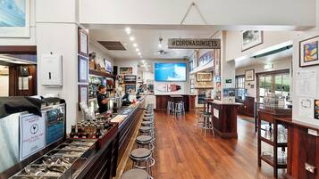 A bar area with stools, a counter, and a television screen.