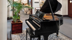 Un piano de cola en un área de recepción, con una planta en maceta a su lado.