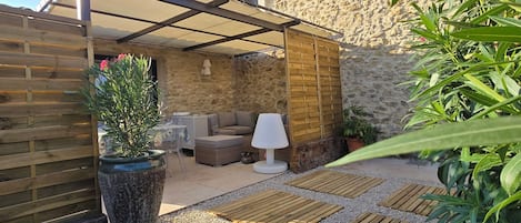 Un espace extérieur abrité, aménagé avec une cloison en pierre, une clôture en bois et un pot de fleurs.