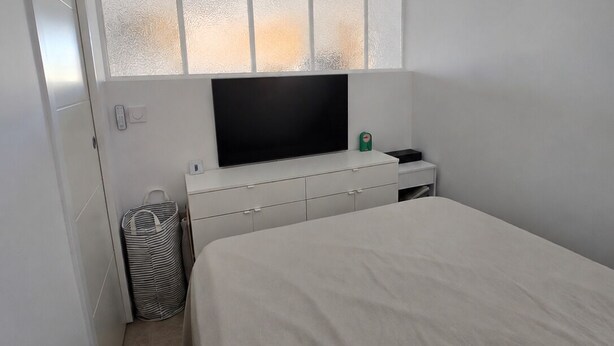 Una camera da letto con un letto, una televisione, un armadio e un piccolo cestino.