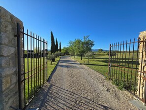 A gravel pathway leading through a fenced area with stone walls and trees.