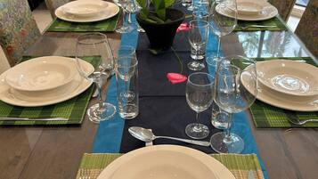 A dining table set with plates, glasses, and cutlery, surrounded by chairs with floral upholstery.