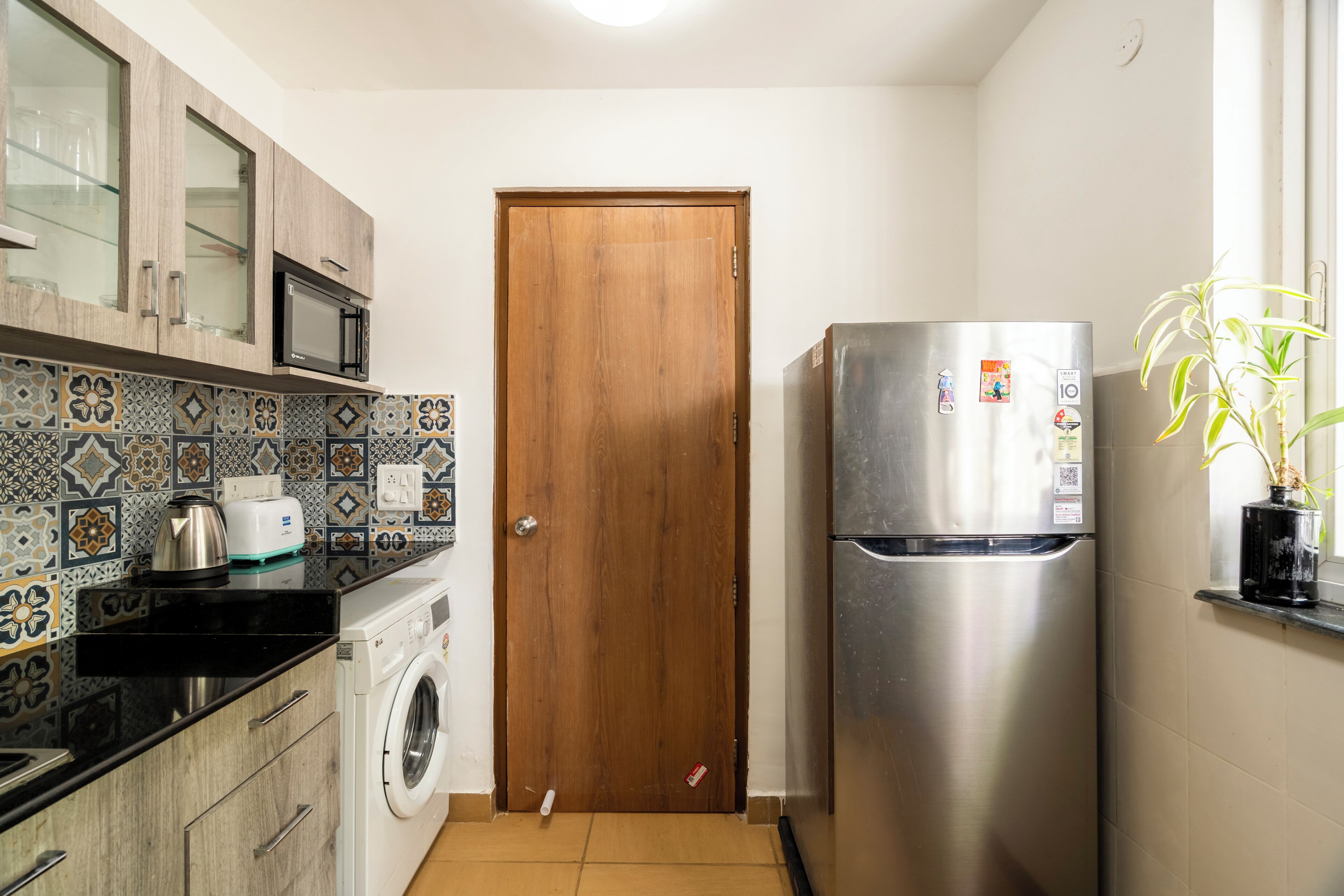 A compact kitchen with a washing machine, a microwave, and a refrigerator.