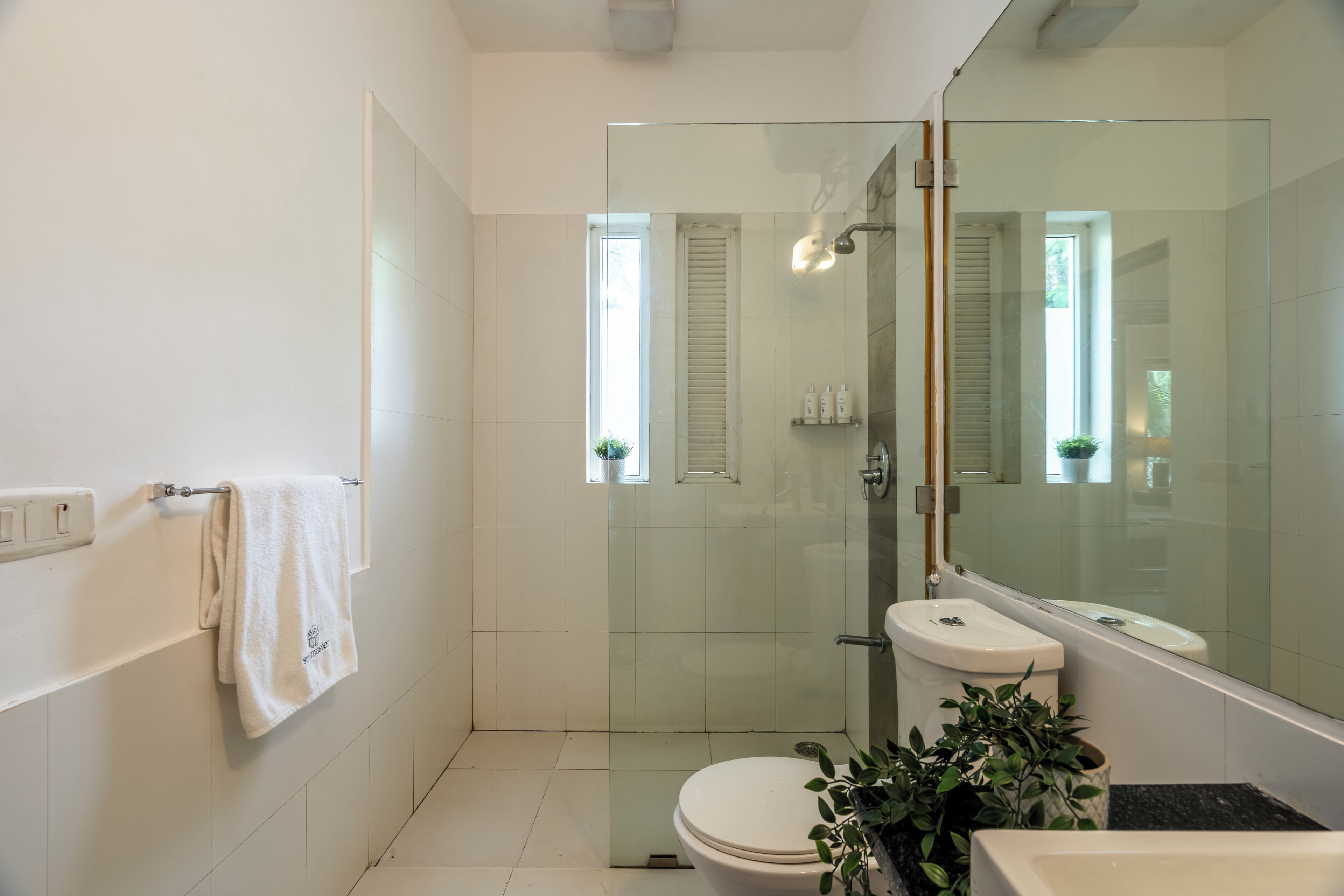 Un baño moderno con cabina de ducha de vidrio, inodoro, lavabo y espejo.