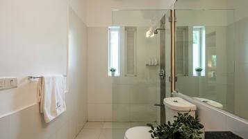 Un baño moderno con cabina de ducha de vidrio, inodoro, lavabo y espejo.