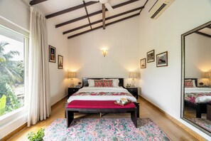 Ein Hotelzimmer mit einem großen Bett, zwei Nachttischen, einem Spiegel und einem Fenster mit Vorhängen.