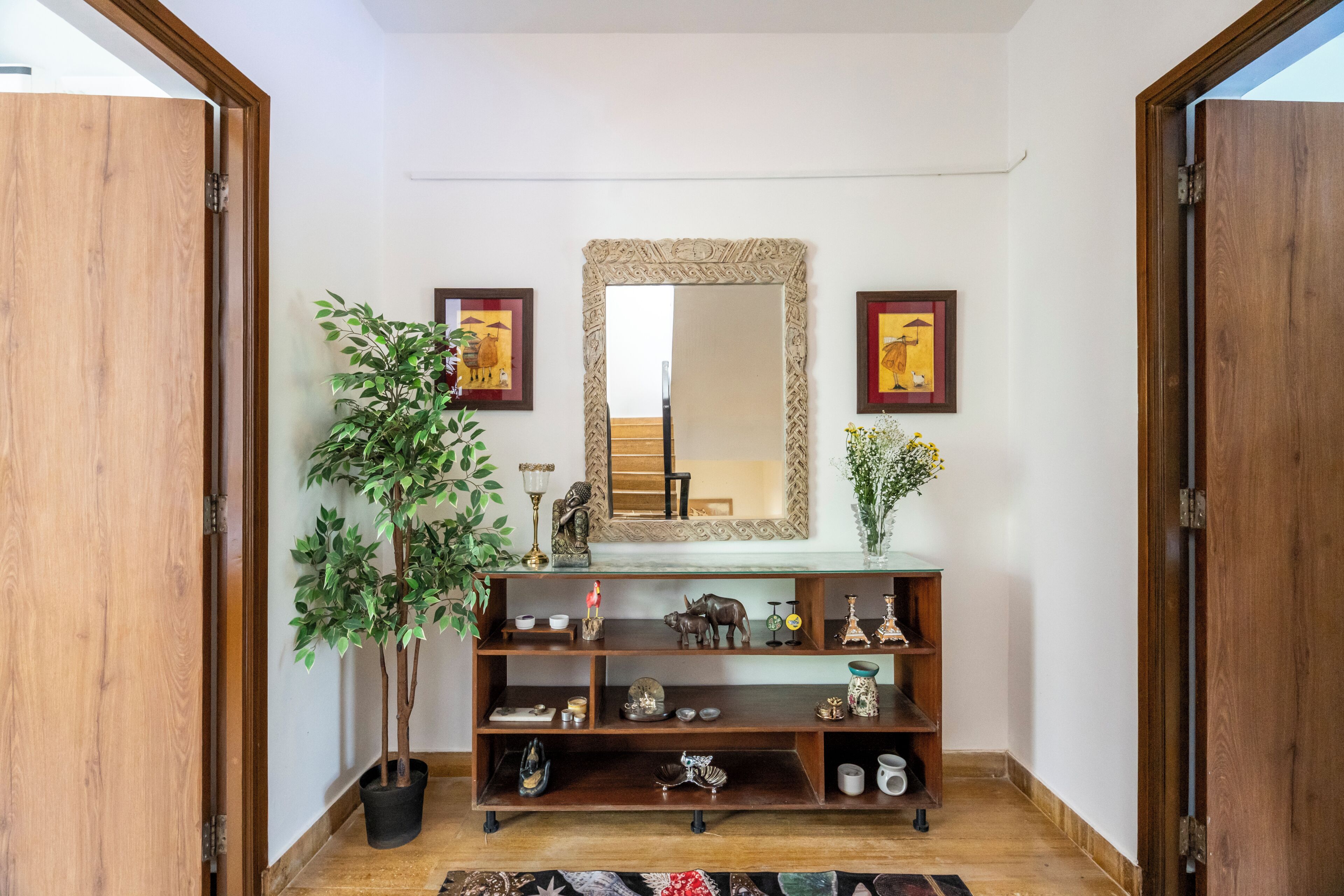 A wooden console table with decorative items, a mirror, and a potted plant in a hallway.