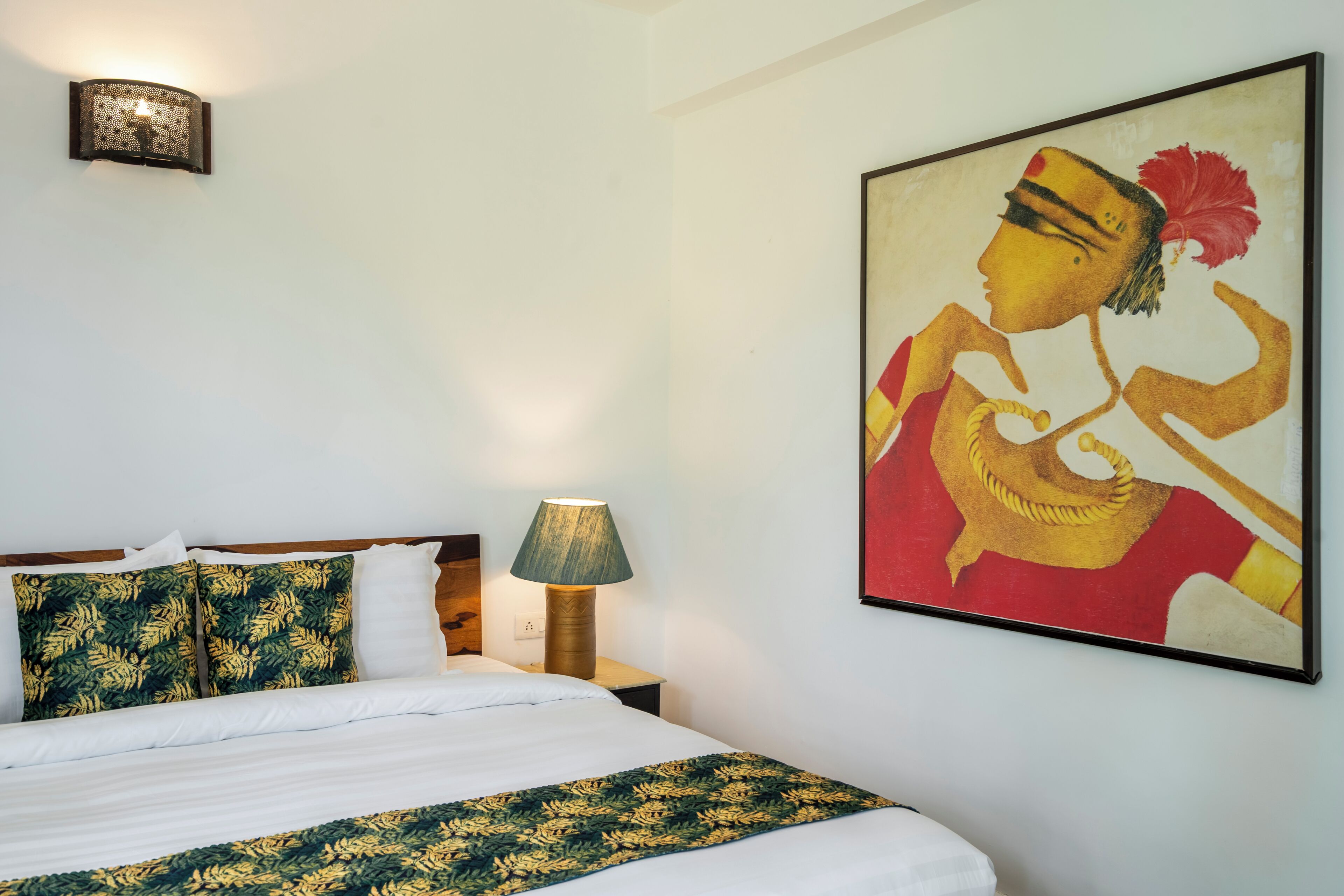 Una habitación de hotel con una cama, una mesita de noche, una lámpara y un cuadro en la pared.