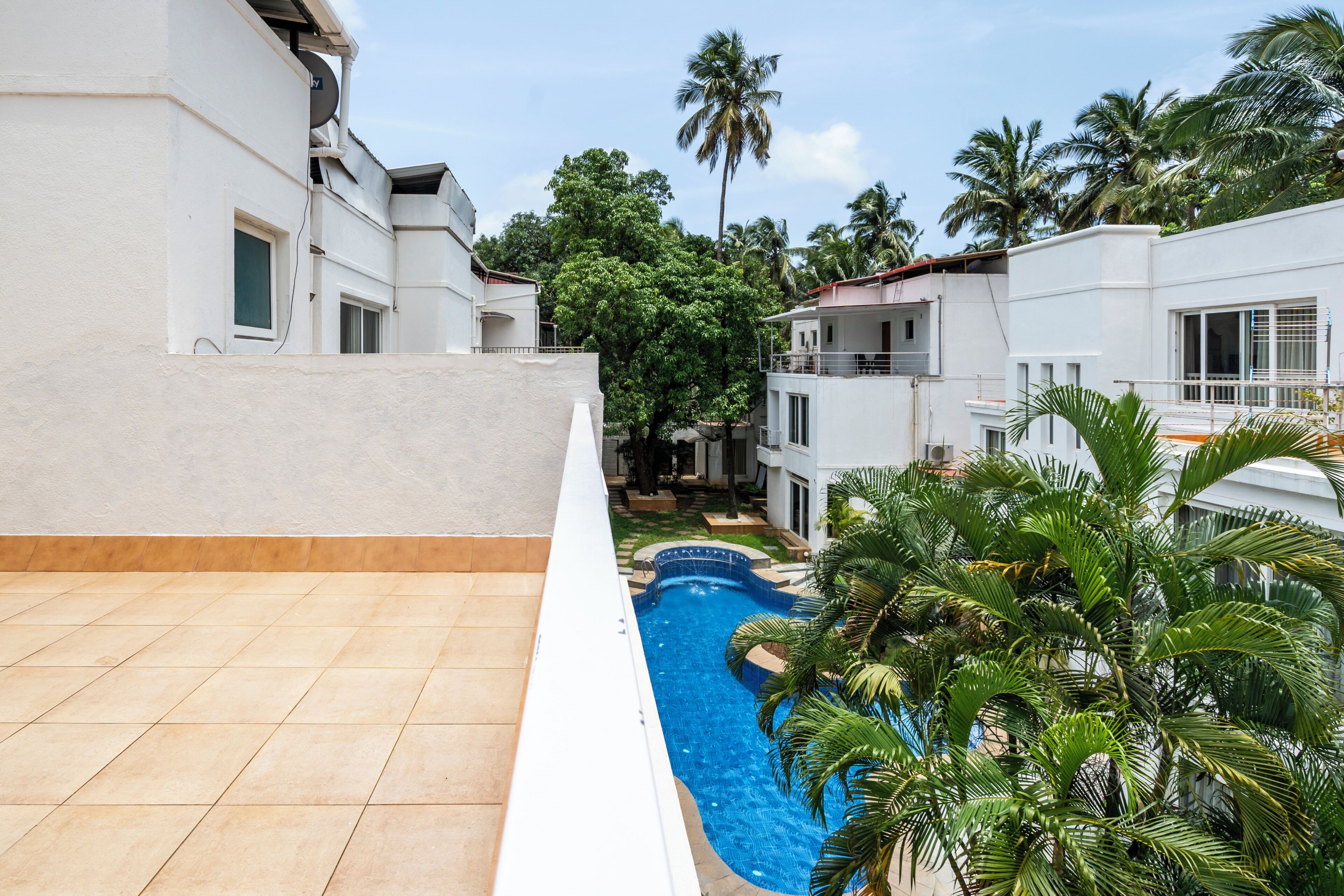 A residential area with a swimming pool, white buildings, and palm trees.