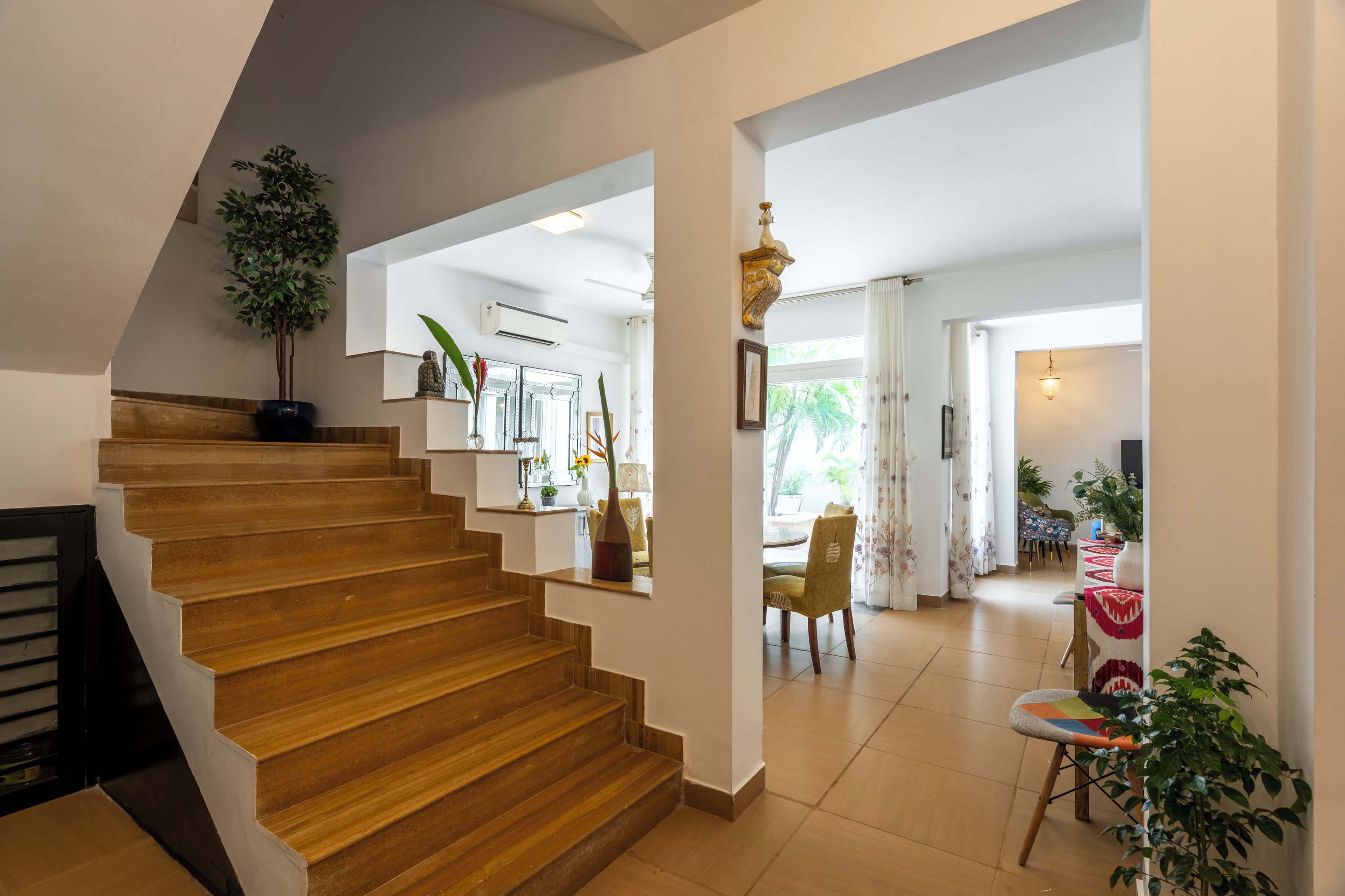 Eine Treppe führt zu einem Wohnbereich mit Esstisch und Stühlen, einer Pflanze und einem Deckenventilator.