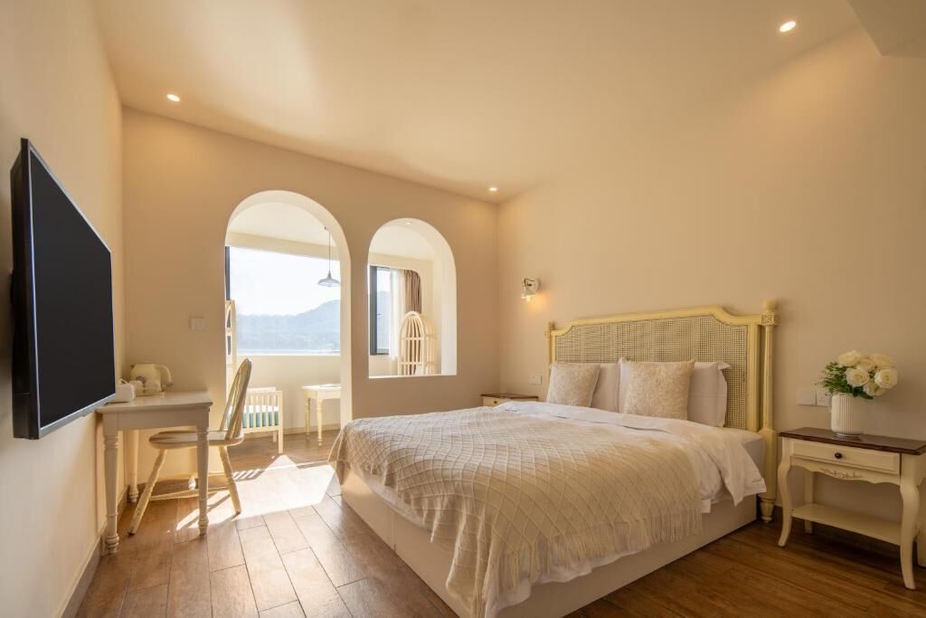 Un dormitorio con cama, escritorio y dos ventanas arqueadas.