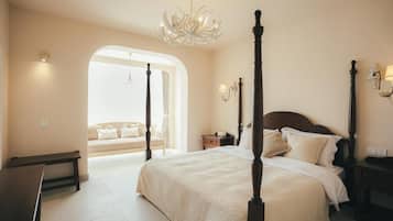 A bedroom with a four-poster bed, a chandelier, and a bench.