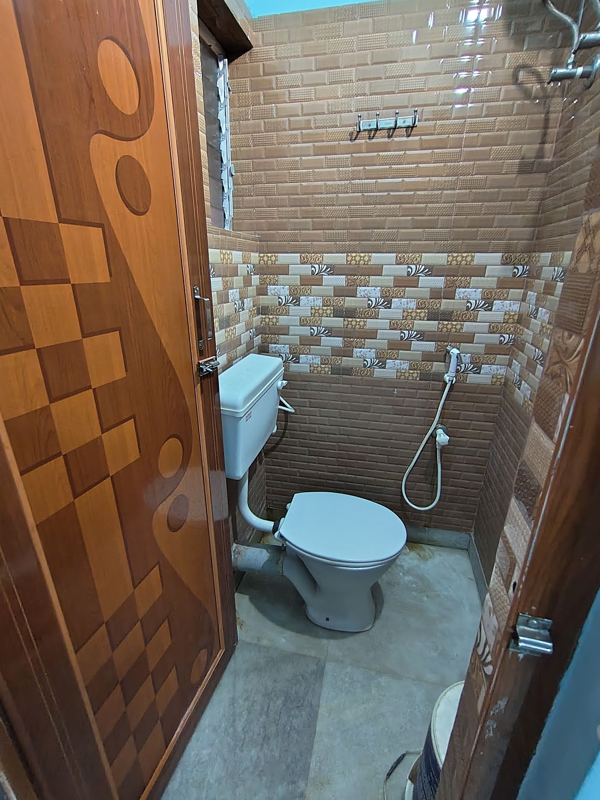 A bathroom with a toilet, a shower, and a tiled wall.