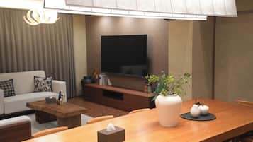 A modern living room with a sofa, coffee table, and a dining table with a vase and a tissue box.