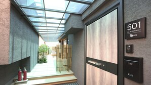 Un pasillo moderno de hotel con techo de vidrio, una puerta de madera con la etiqueta '501' y un extintor de incendios a la izquierda.