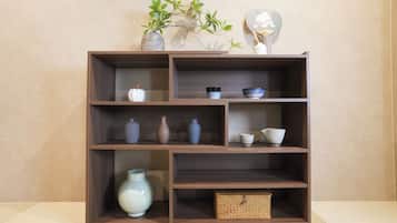 A wooden shelf unit with multiple compartments, some containing vases and bowls, and a small woven basket.