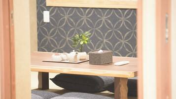 A room with a wooden table, a small plant, a tissue box, and a remote control.