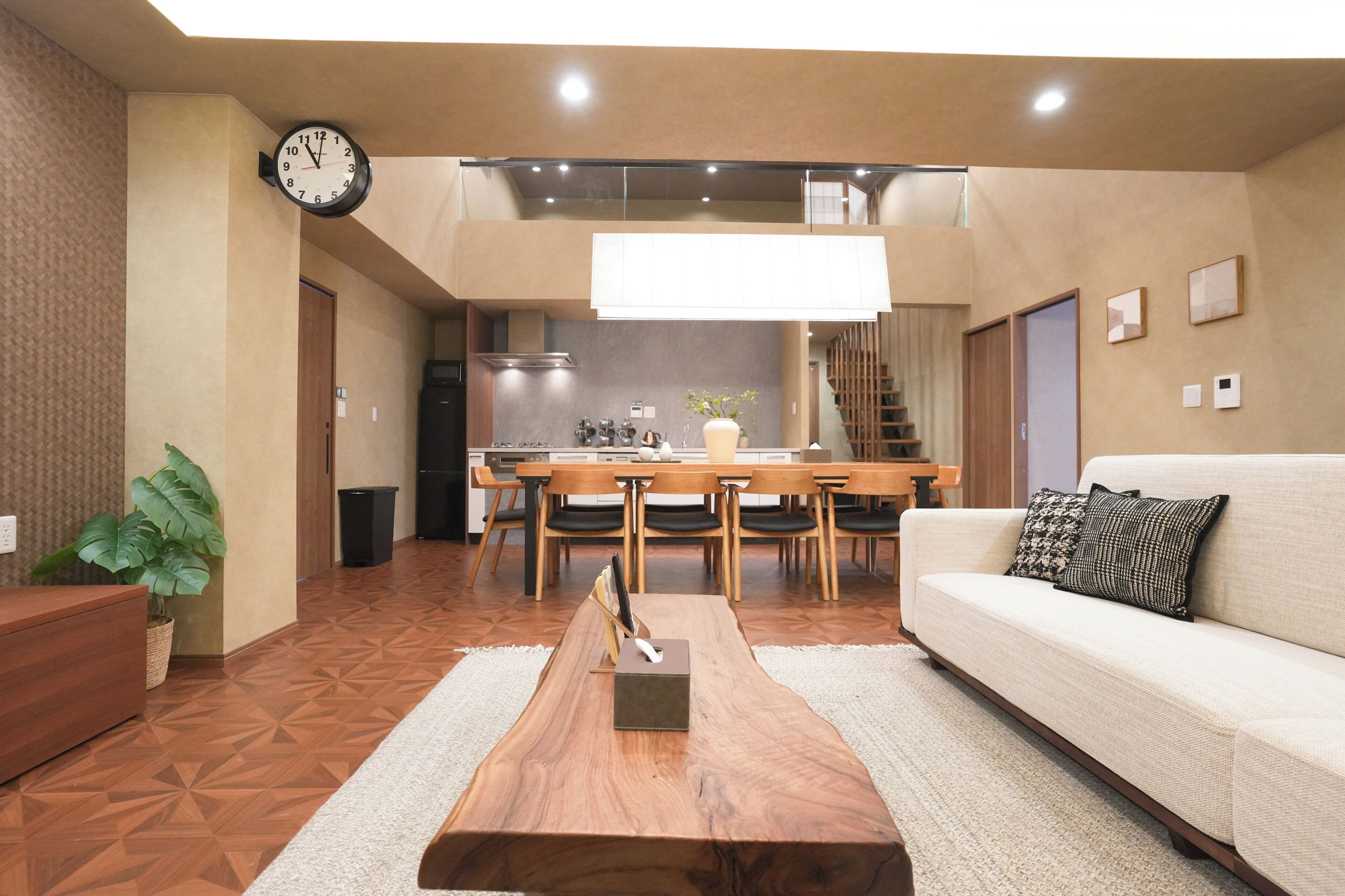 A modern living room with a sofa, coffee table, and a dining area with chairs and a table.