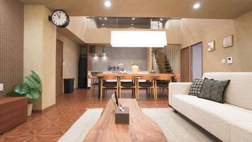 A modern living room with a sofa, coffee table, and a dining area with chairs and a table.