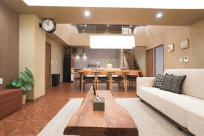 Una sala de estar moderna con sofá, mesa de centro y una zona de comedor con sillas y una mesa.