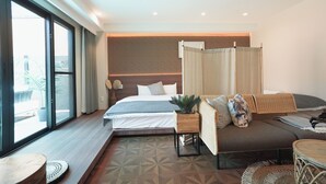 Una habitación de hotel moderna con una cama grande, un sofá, una mesita y vistas amplias por un ventanal.