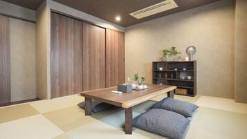 A room with a wooden table, cushions, a shelf with decorative items, and a sliding door.