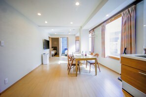 A spacious room with a dining area, a kitchenette, and a large window with curtains. - Glowlight 201 - 4-Bedroom Family Suite - 2-Minute Walk to Kuromon Market (Osaka)