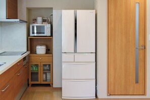 A compact kitchen with a white refrigerator, a microwave, and a bread maker on a wooden countertop. - SERENE | Kuromon ・ 201 | 4BR ・ 2 Shower Rooms | Private Home for Families and Groups (Osaka)