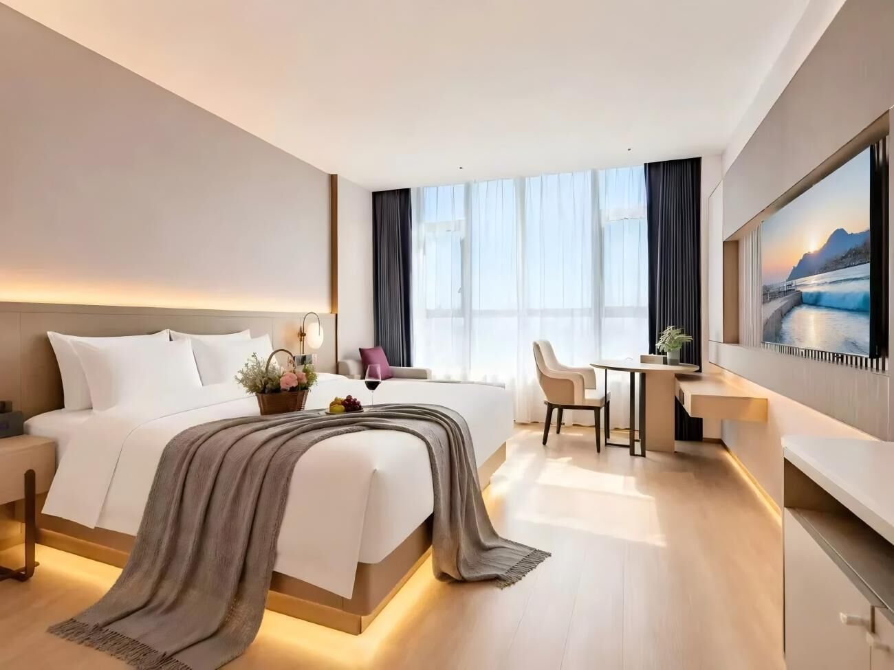 A modern hotel room with a large bed, a desk, and a television.