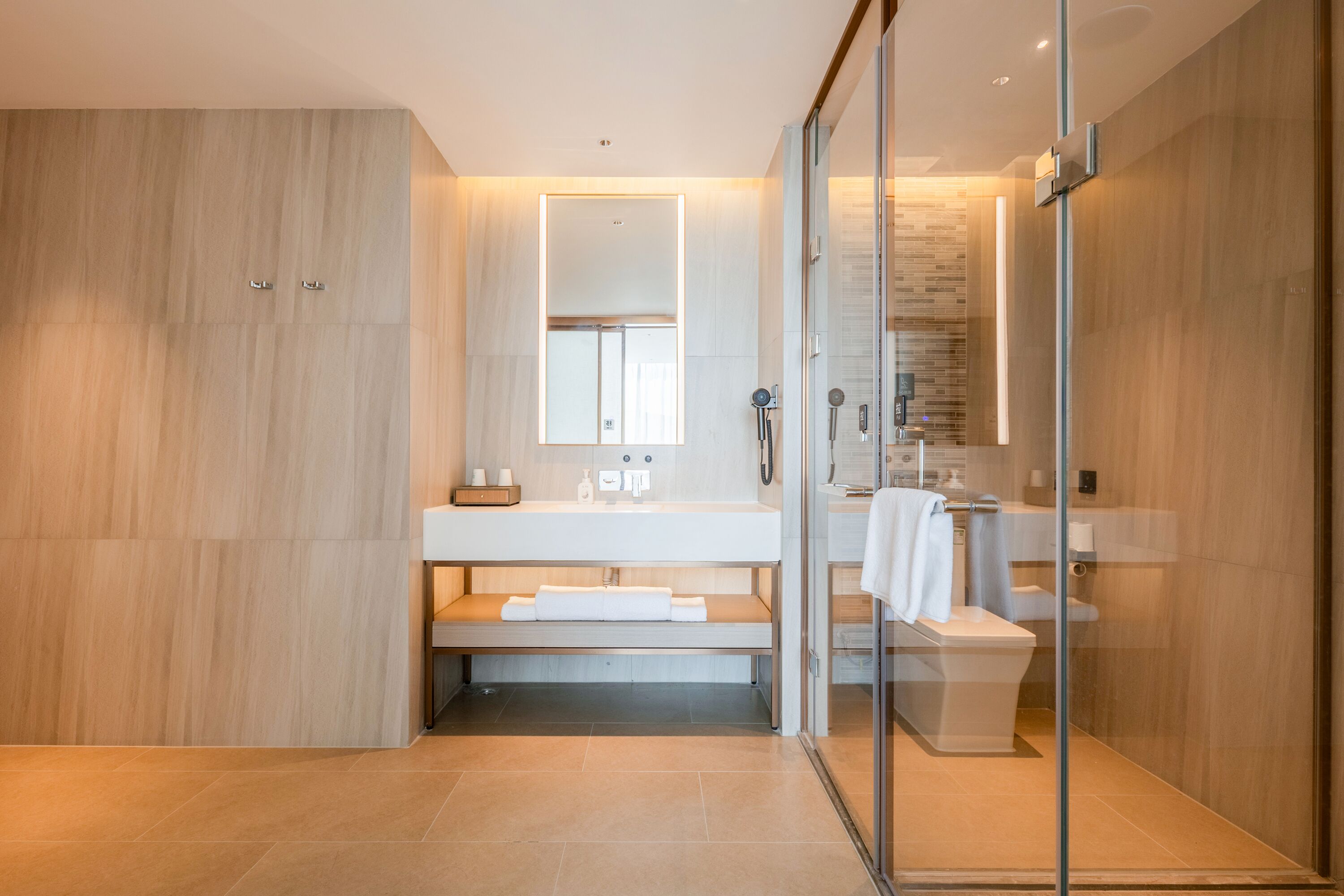 A modern bathroom with a glass shower enclosure, a wooden vanity, and a large mirror.