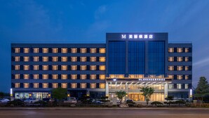 A modern hotel building with a prominent 'M' sign on the facade, multiple floors, and a covered entrance area. - Meilifeng Hotel  (Weihai)