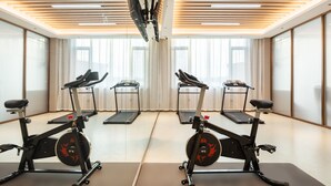 A gym with treadmills and stationary bikes, large windows, and a modern ceiling design. - Meilifeng Hotel  (Weihai)