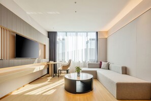 Una sala de estar moderna con un televisor de pantalla plana, una mesa redonda, un sofá y una zona de comedor con mesa y sillas.
