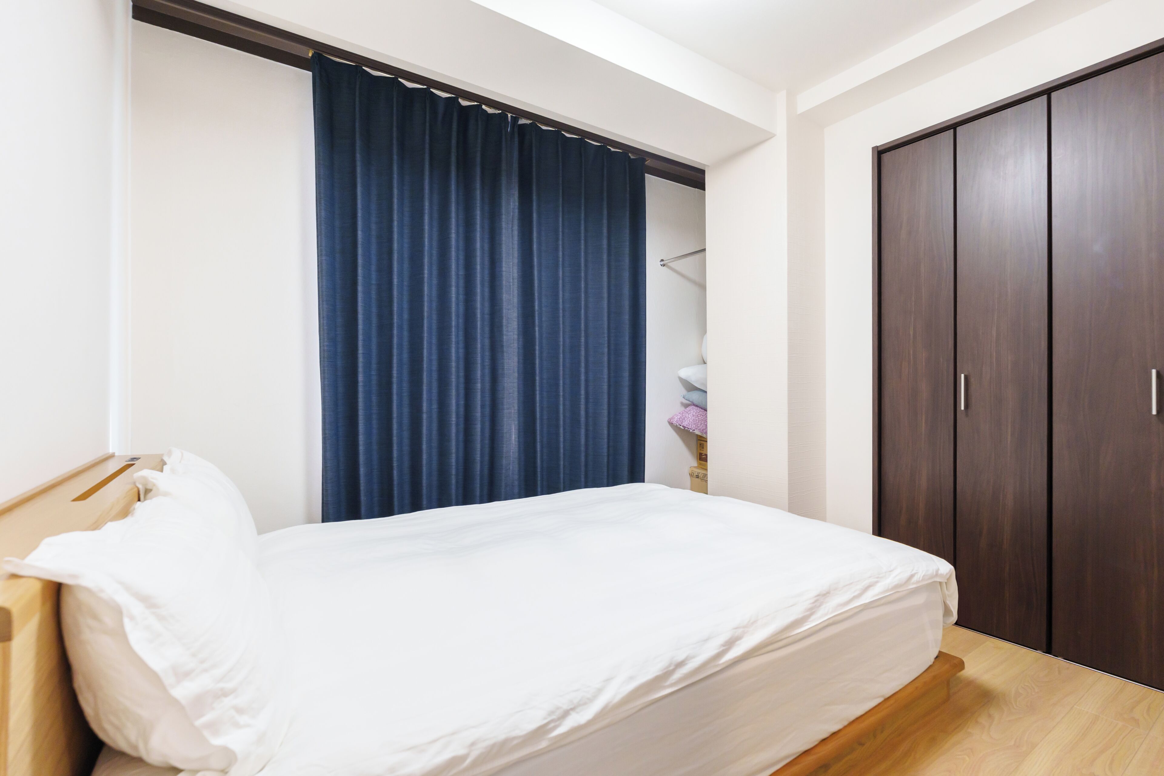 A hotel room with a bed, a wardrobe, and a curtain.