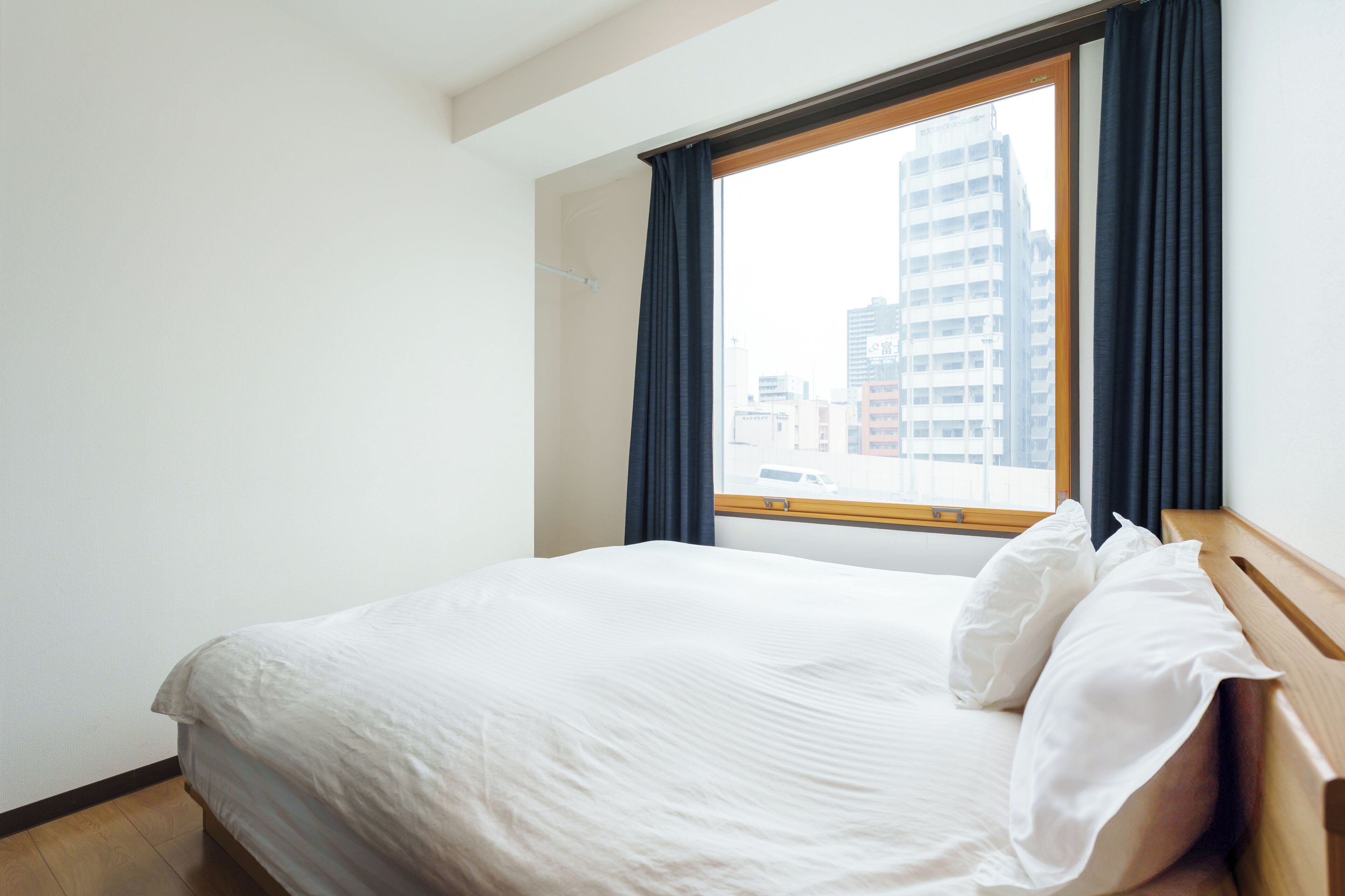 Una habitación de hotel con una cama grande, una ventana con cortinas y vistas a edificios altos.
