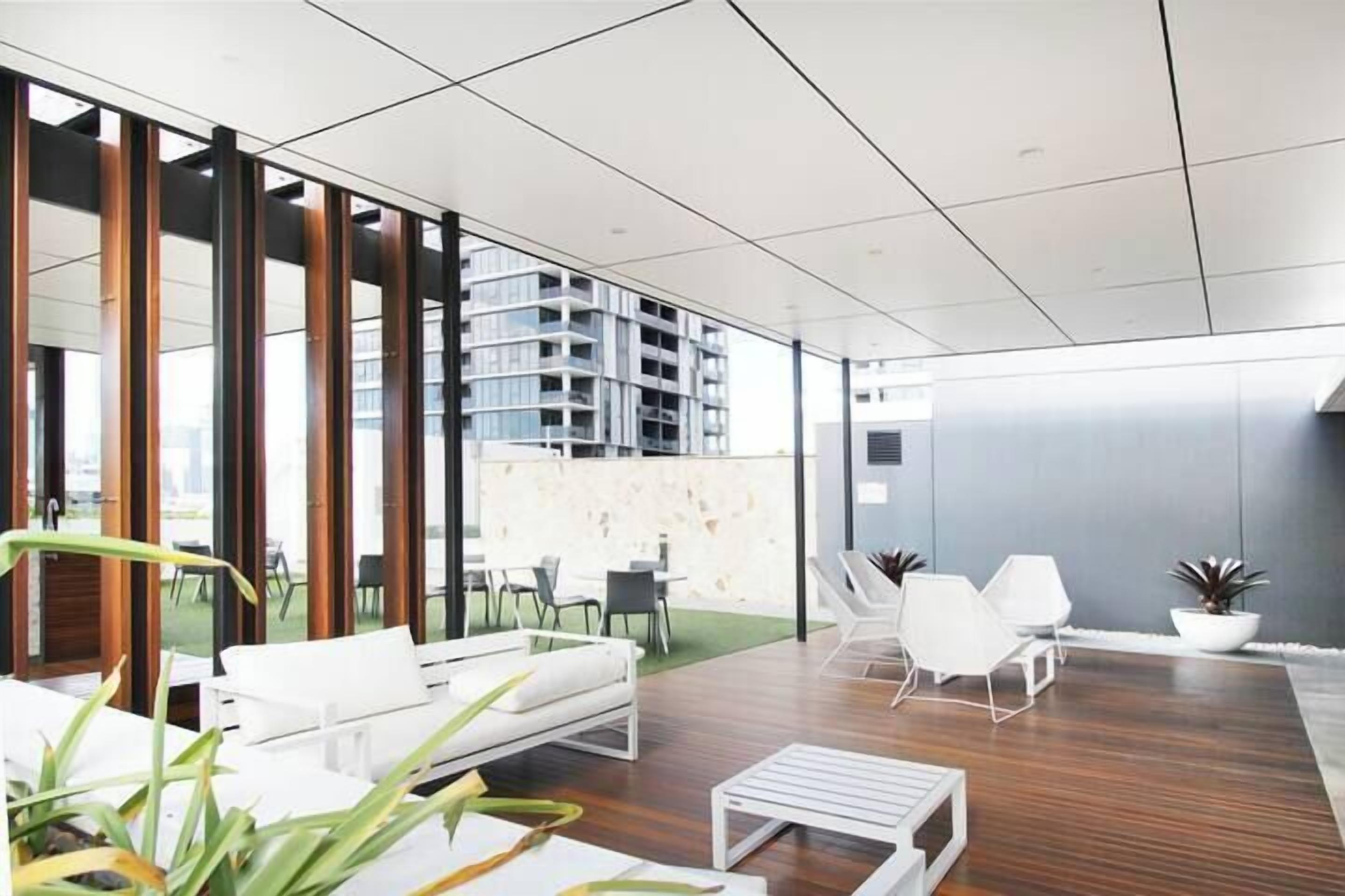 A modern lounge area with a white sofa, white chairs, and a small table.