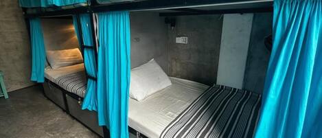 A bunk bed room with curtains, a power outlet, and a small table.