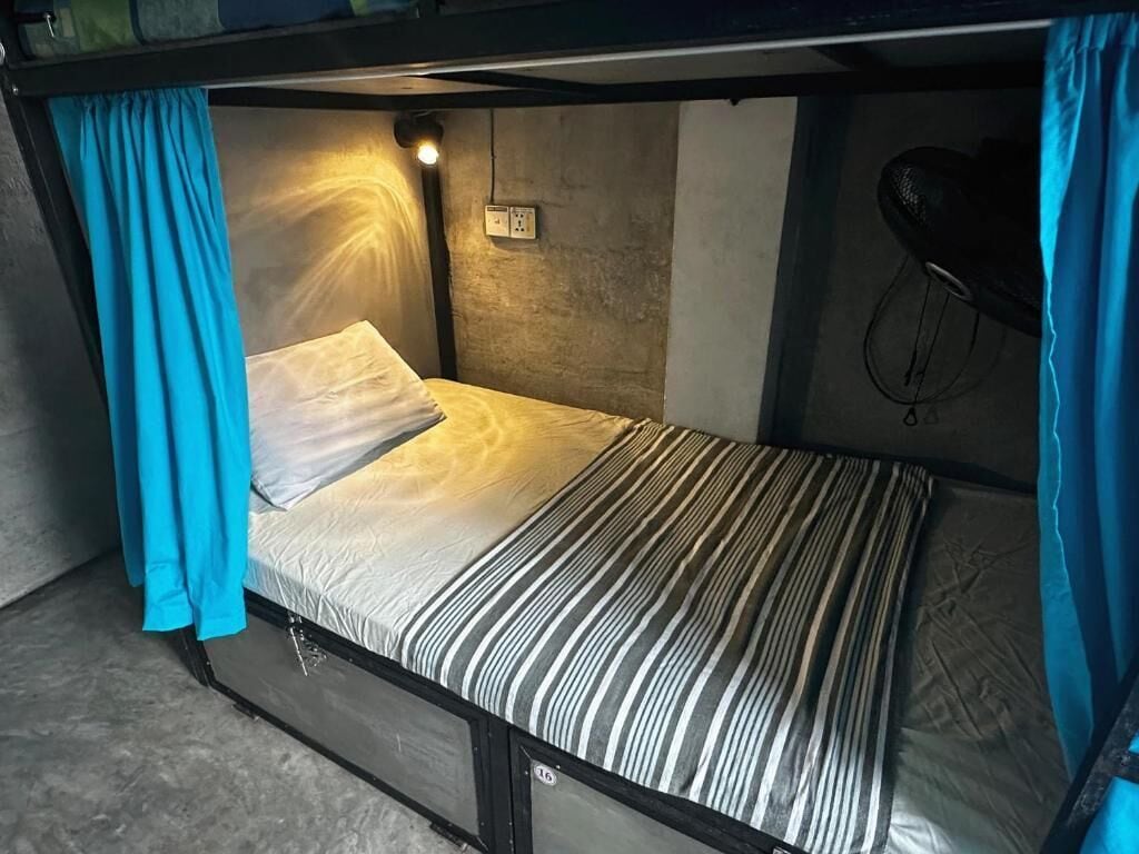 Een stapelbed met hoofdbord, een stopcontact en een fietsenrek aan de muur.