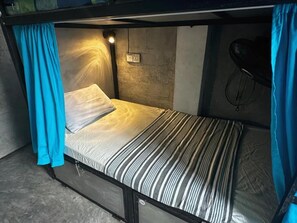 A bunk bed with a headboard, a power outlet, and a wall-mounted bike rack. - Cycling Backpacker Hostel (Unawatuna)