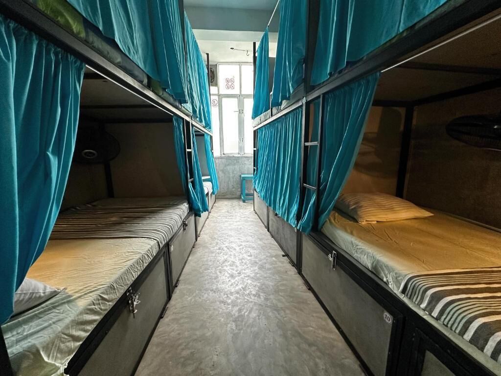 A narrow corridor with bunk beds on either side, each with a curtain.