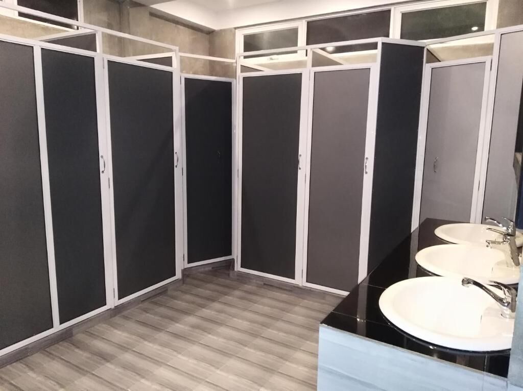 A bathroom with a wooden floor, a black vanity with a mirror, and three sinks.