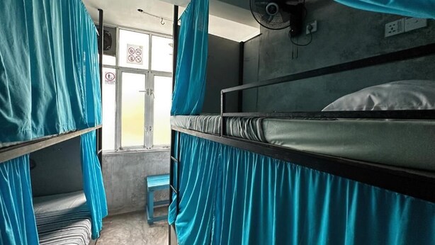 Un dormitorio con literas, un ventilador y una ventana con cortinas.